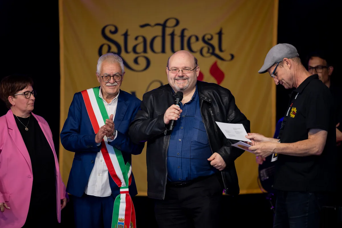 Zwei Herren feiern auf der Bühne an einem Stadtfest. 